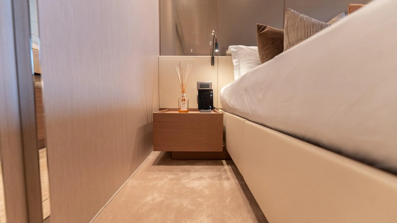 A cozy guest stateroom featuring a neatly made bed and a modern nightstand. aboard LA Yacht for Sale
