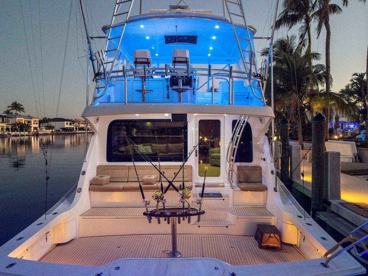 The aft deck of this yacht features a well-equipped fishing setup and comfortable seating under ambient blue lighting. aboard REEL TEXAN Yacht for Sale