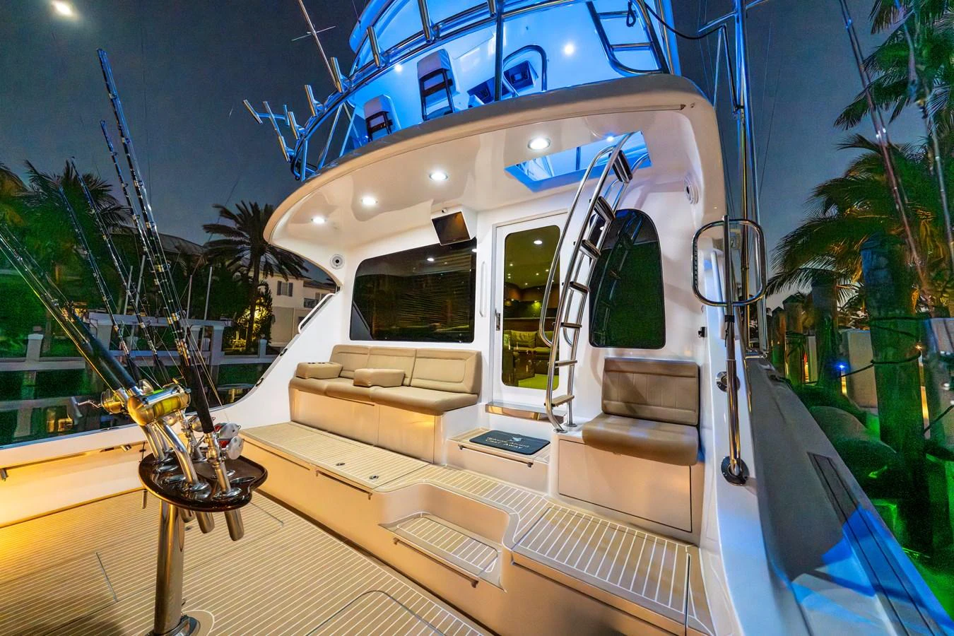 The aft deck of this yacht features comfortable seating and fishing equipment, illuminated by ambient lighting. aboard REEL TEXAN Yacht for Sale