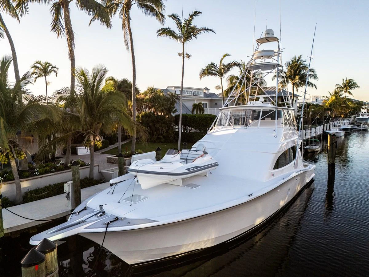 A sleek white yacht is docked in a serene marina surrounded by palm trees. aboard REEL TEXAN Yacht for Sale