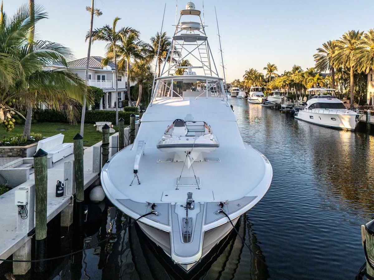 A sleek yacht is docked in a serene marina surrounded by palm trees and waterfront homes. aboard REEL TEXAN Yacht for Sale