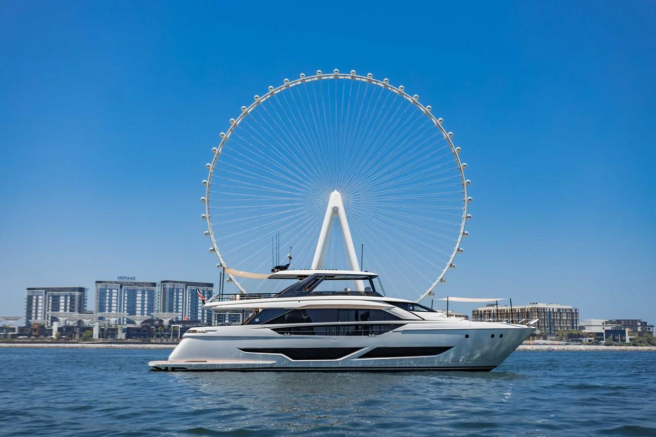 A sleek yacht glides on the water with a cityscape and Ferris wheel in the background. aboard CYRUS Yacht for Sale