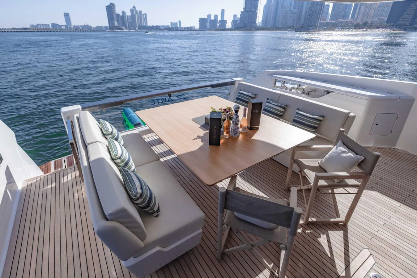 The aft deck features a stylish dining area with comfortable seating and a beautiful view of the city skyline. aboard CYRUS Yacht for Sale