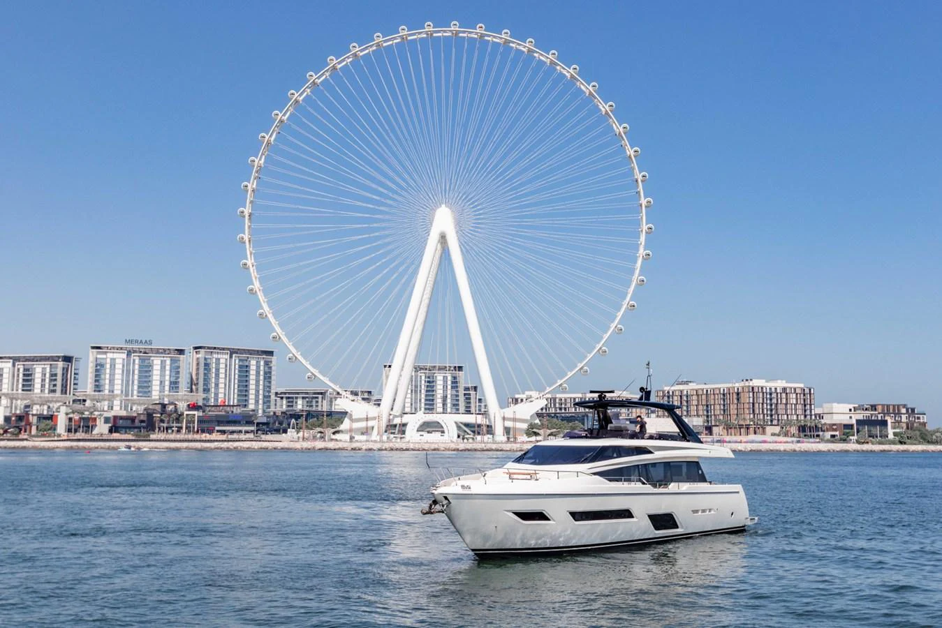 A sleek yacht cruises in front of a stunning cityscape with a giant Ferris wheel. aboard BELLA III Yacht for Sale
