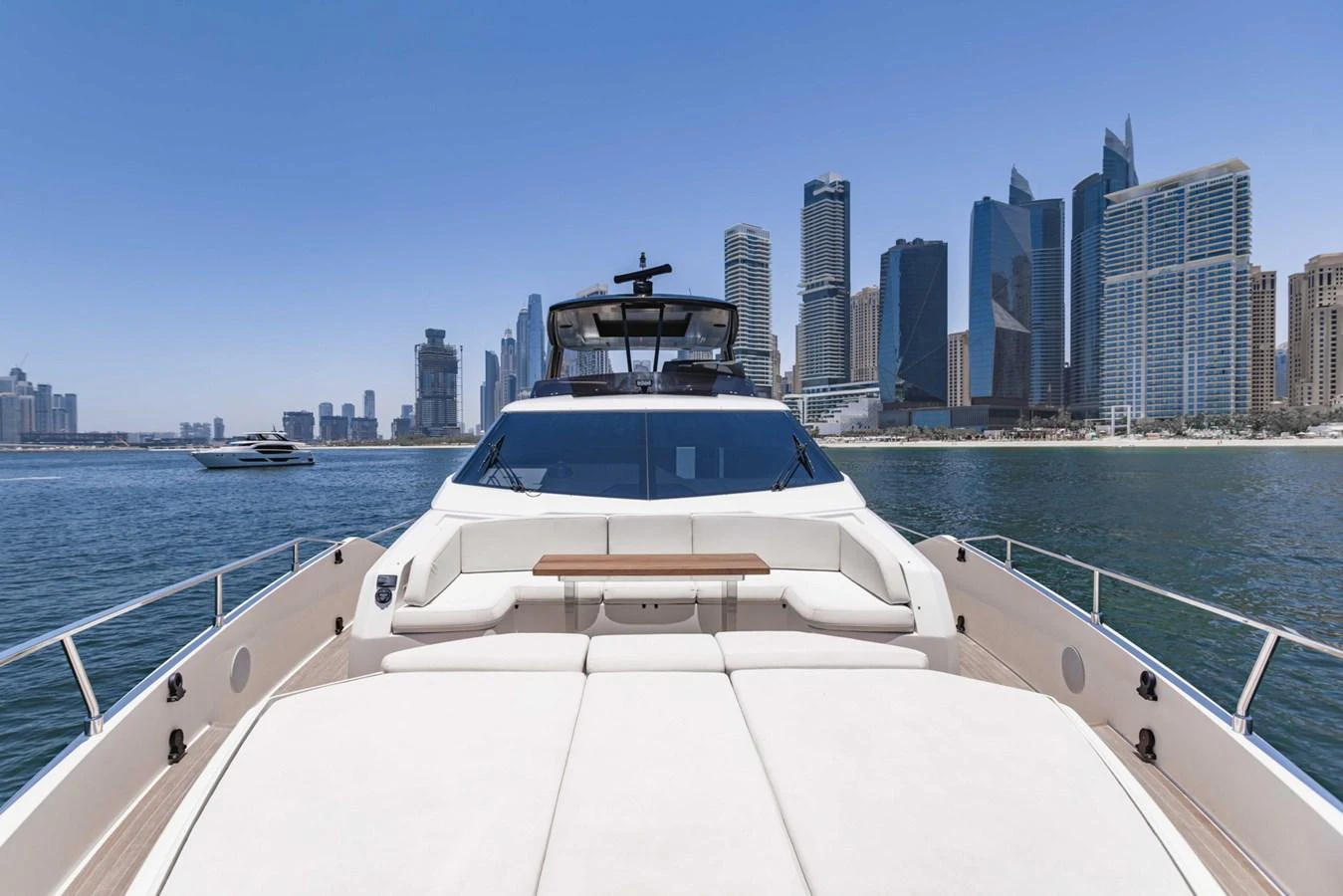 The yacht's foredeck offers a luxurious sunbathing area with a stunning city skyline in the background. aboard BELLA III Yacht for Sale