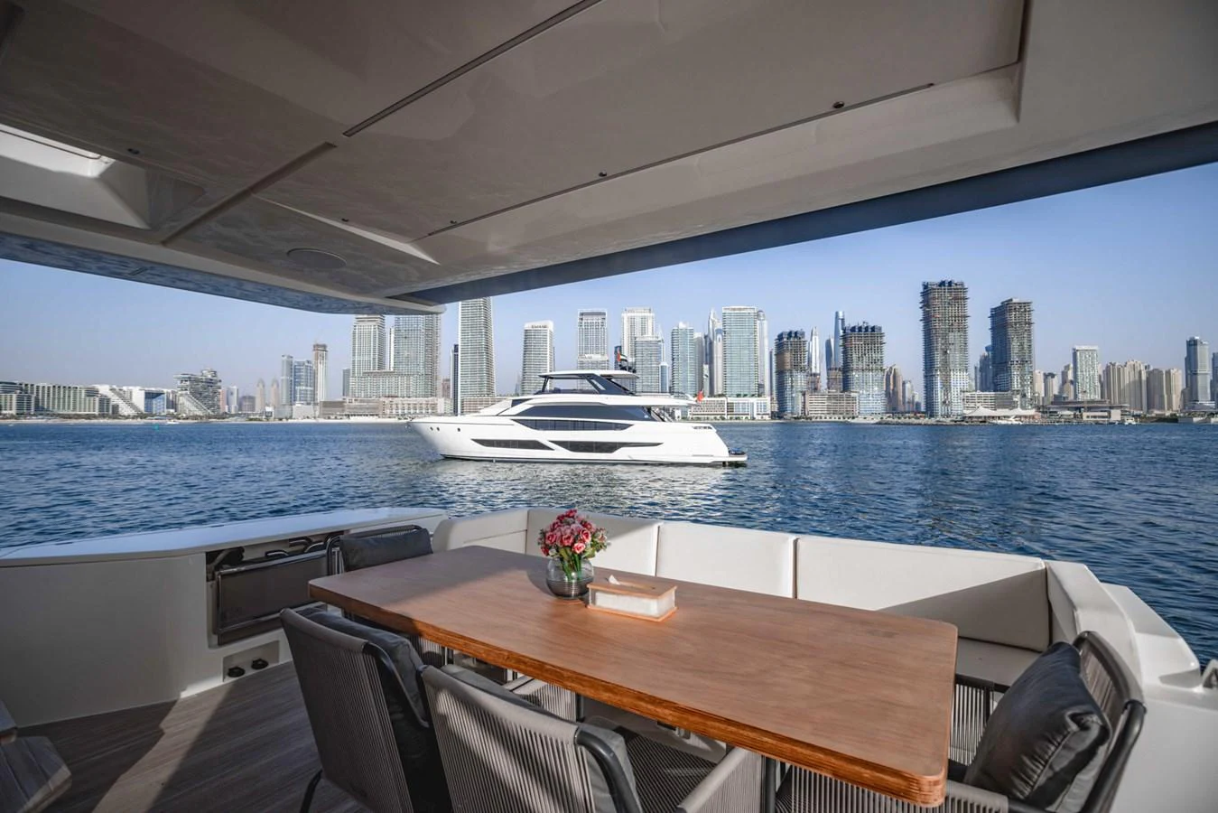 The aft deck offers a stunning view of the city skyline and a sleek yacht cruising by. aboard BELLA III Yacht for Sale