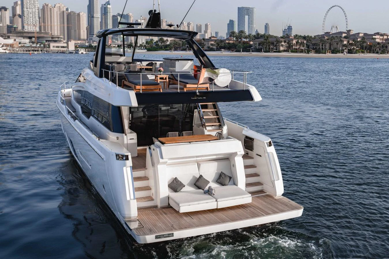 The yacht's aft deck features a luxurious seating area with a stunning cityscape in the background. aboard BELLA III Yacht for Sale