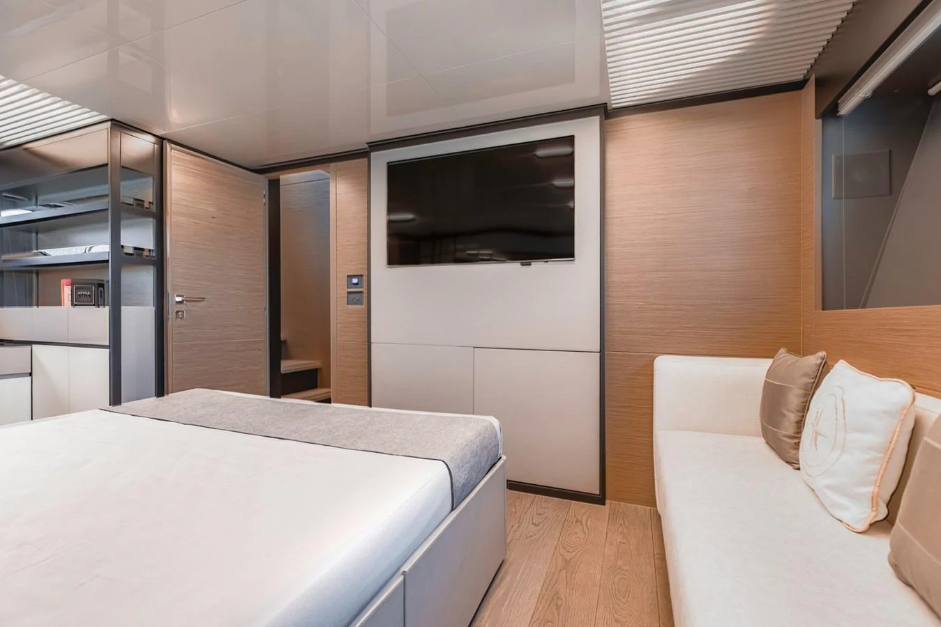 The stateroom features a modern design with a large bed, a wall-mounted TV, and a comfortable seating area. aboard BELLA III Yacht for Sale