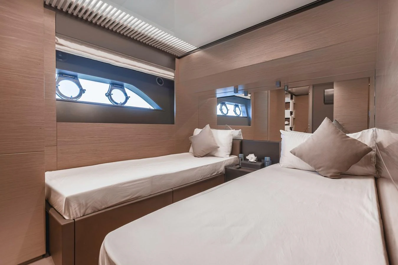The guest stateroom features twin beds, modern decor, and ample natural light from the windows. aboard BELLA III Yacht for Sale