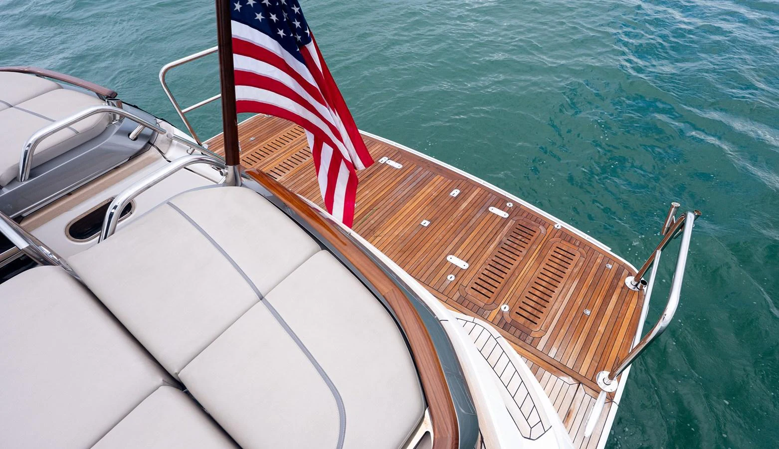 The yacht's aft deck features a spacious teak platform with an American flag waving in the breeze. aboard PARAGON Yacht for Sale