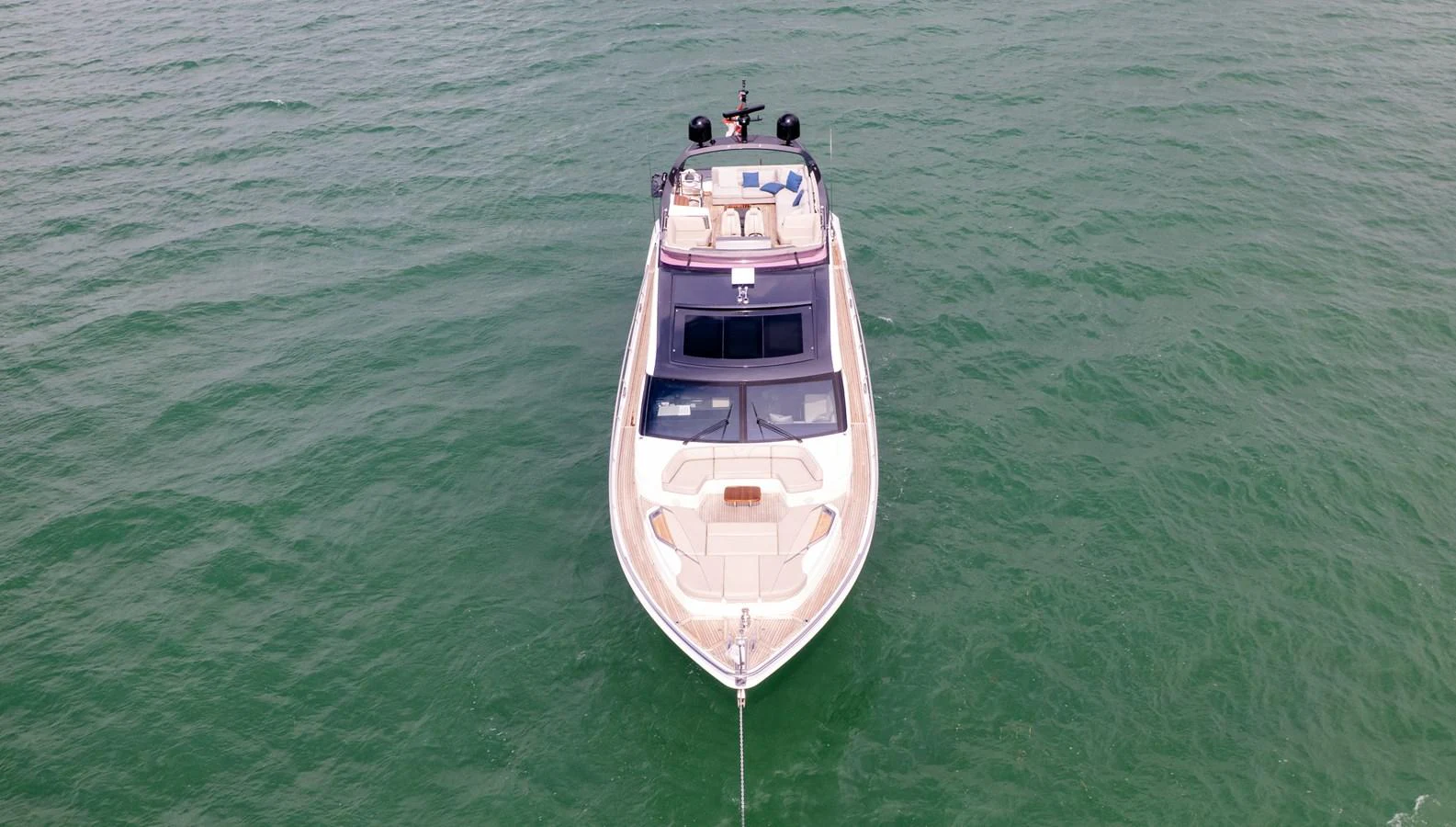 A sleek yacht cruises gracefully on calm green waters, showcasing its elegant design from a top-down perspective. aboard PARAGON Yacht for Sale