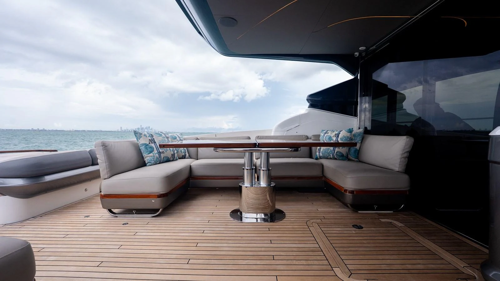 The aft deck features a spacious seating area with plush cushions and a sleek wooden table, perfect for outdoor relaxation. aboard PARAGON Yacht for Sale
