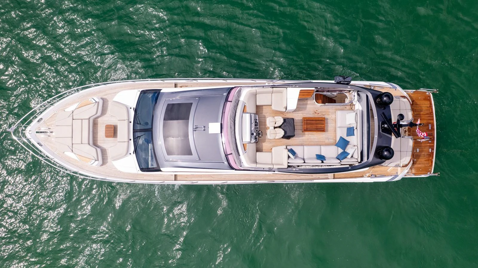 An aerial view of a sleek yacht cruising on calm green waters, showcasing its spacious deck and luxurious amenities. aboard PARAGON Yacht for Sale