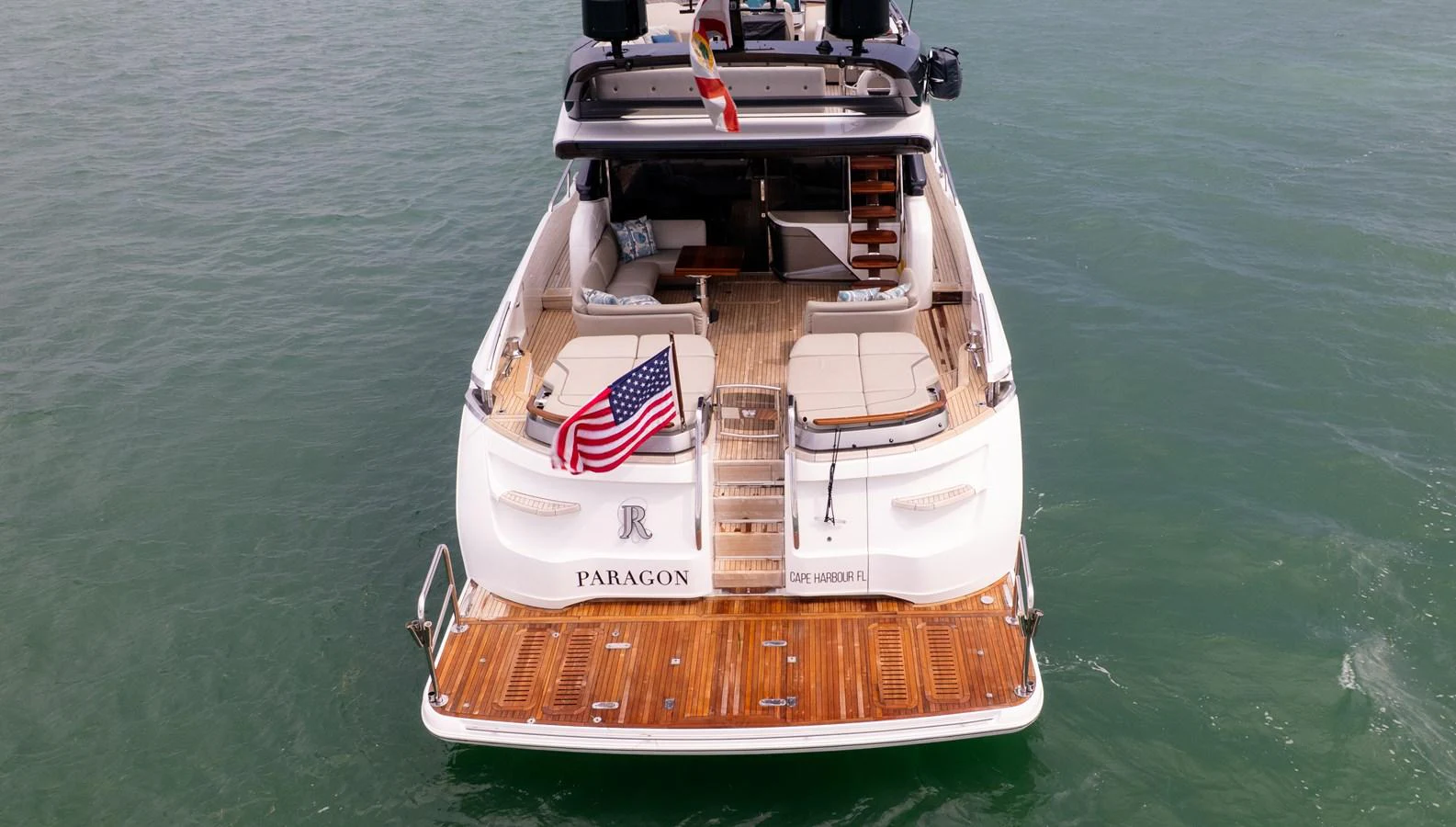 The yacht's aft deck features a spacious lounging area with comfortable seating and a wooden swim platform. aboard PARAGON Yacht for Sale