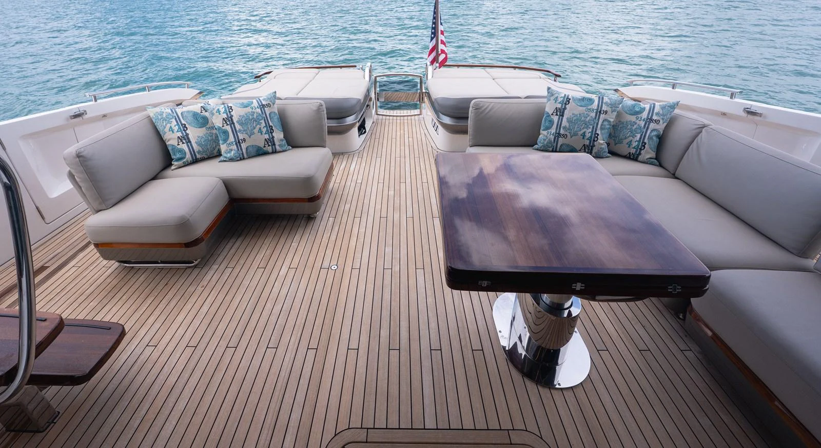 The aft deck features comfortable seating with plush cushions and a polished wooden table, perfect for relaxation and socializing. aboard PARAGON Yacht for Sale