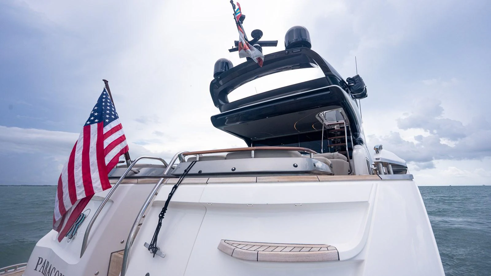 The yacht's stern features a spacious deck with an American flag waving in the breeze. aboard PARAGON Yacht for Sale