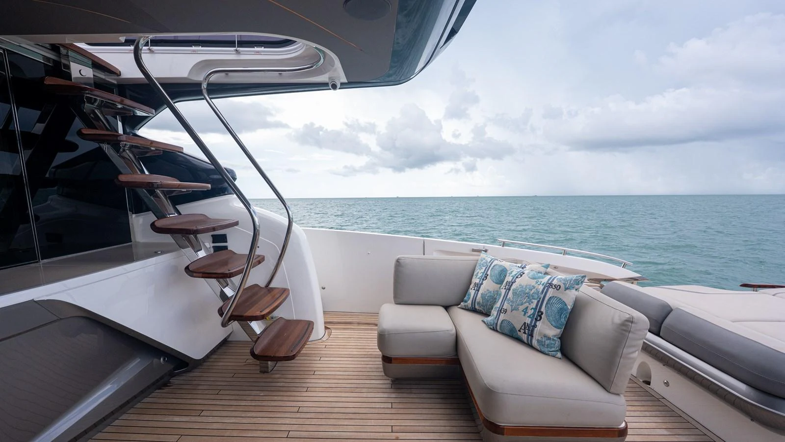The aft deck features a stylish seating area with a modern staircase leading to the upper deck, offering a serene view of the open sea. aboard PARAGON Yacht for Sale
