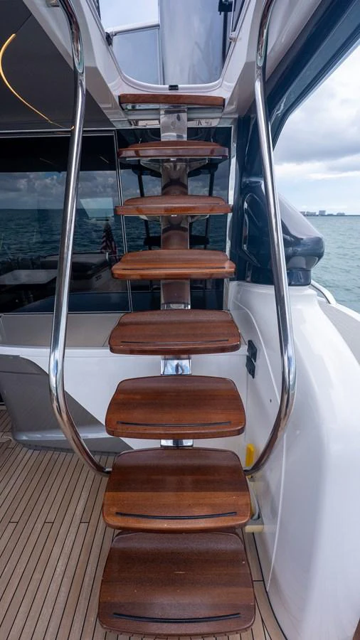 A sleek wooden staircase with stainless steel railings leads to the upper deck. aboard PARAGON Yacht for Sale