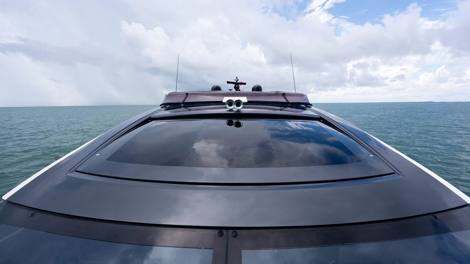 The yacht's sleek, modern bow cuts through the serene waters under a partly cloudy sky. aboard PARAGON Yacht for Sale
