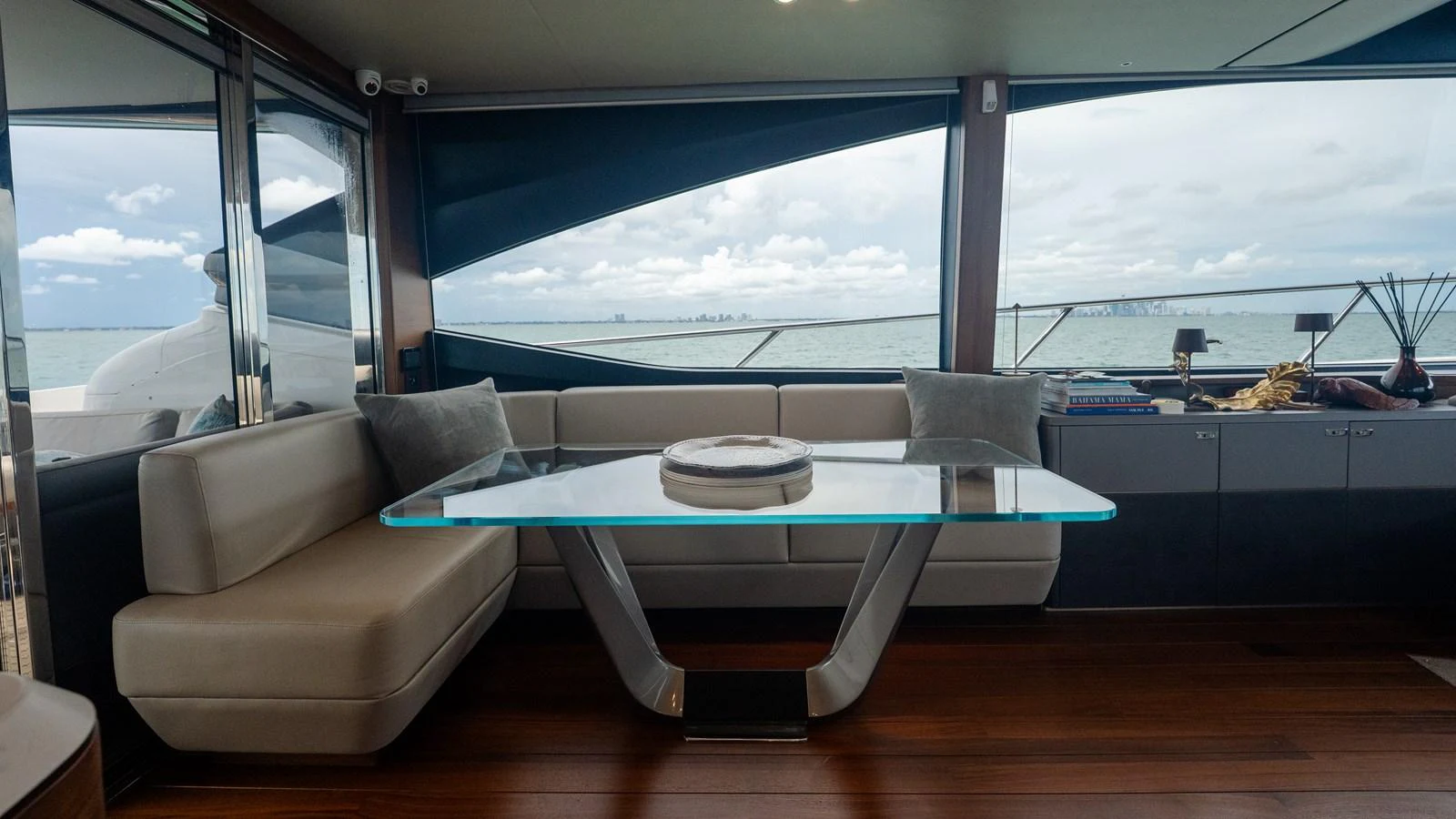 The yacht's salon features a modern glass dining table with plush seating and expansive windows offering stunning sea views. aboard PARAGON Yacht for Sale