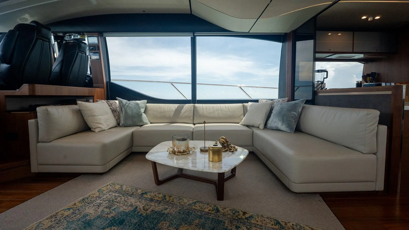 The salon features a luxurious seating area with a large L-shaped sofa and a stylish coffee table, offering panoramic views through expansive windows. aboard PARAGON Yacht for Sale