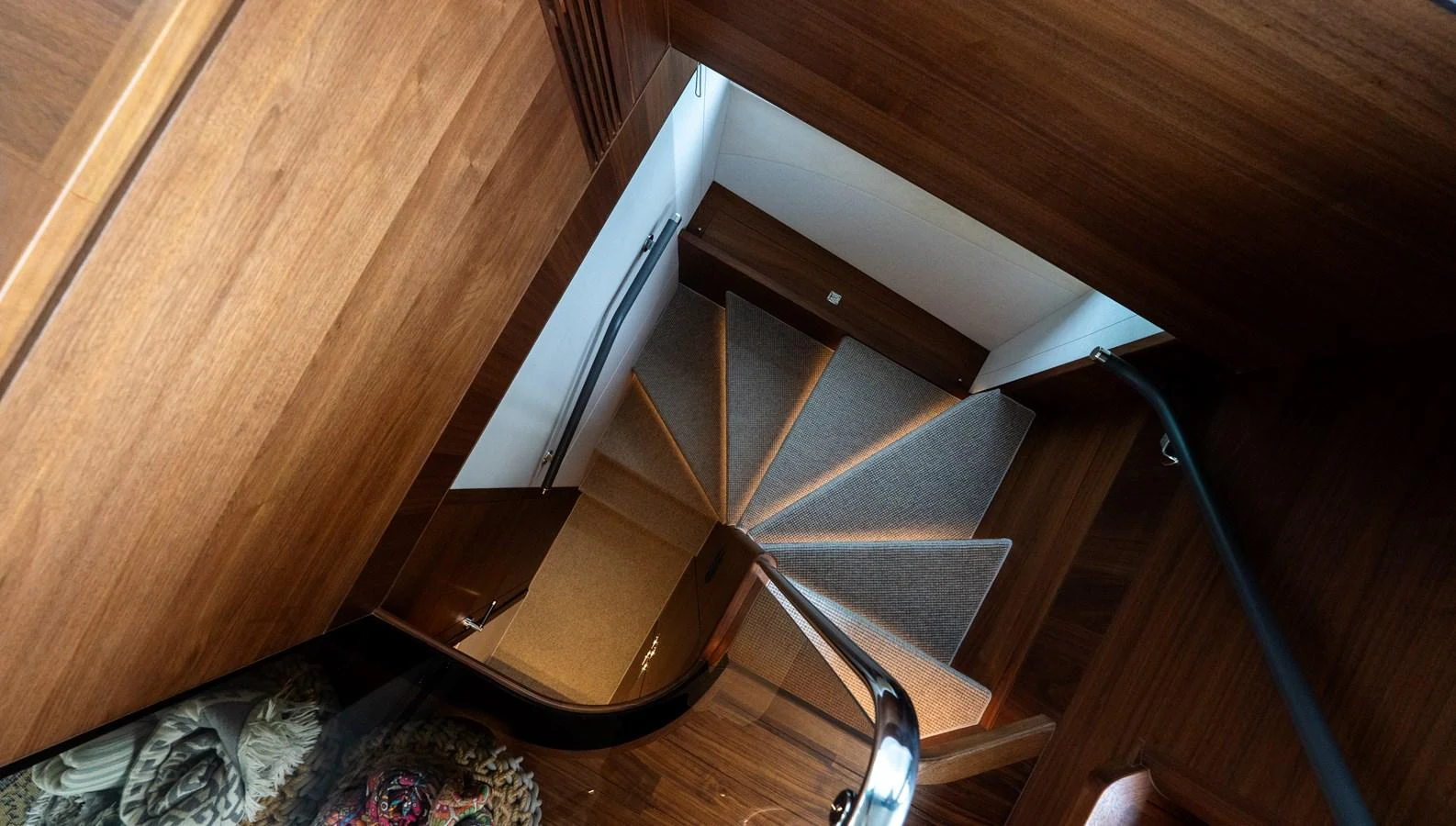 A stylish wooden staircase leads to the lower deck, showcasing the yacht's elegant interior design. aboard PARAGON Yacht for Sale
