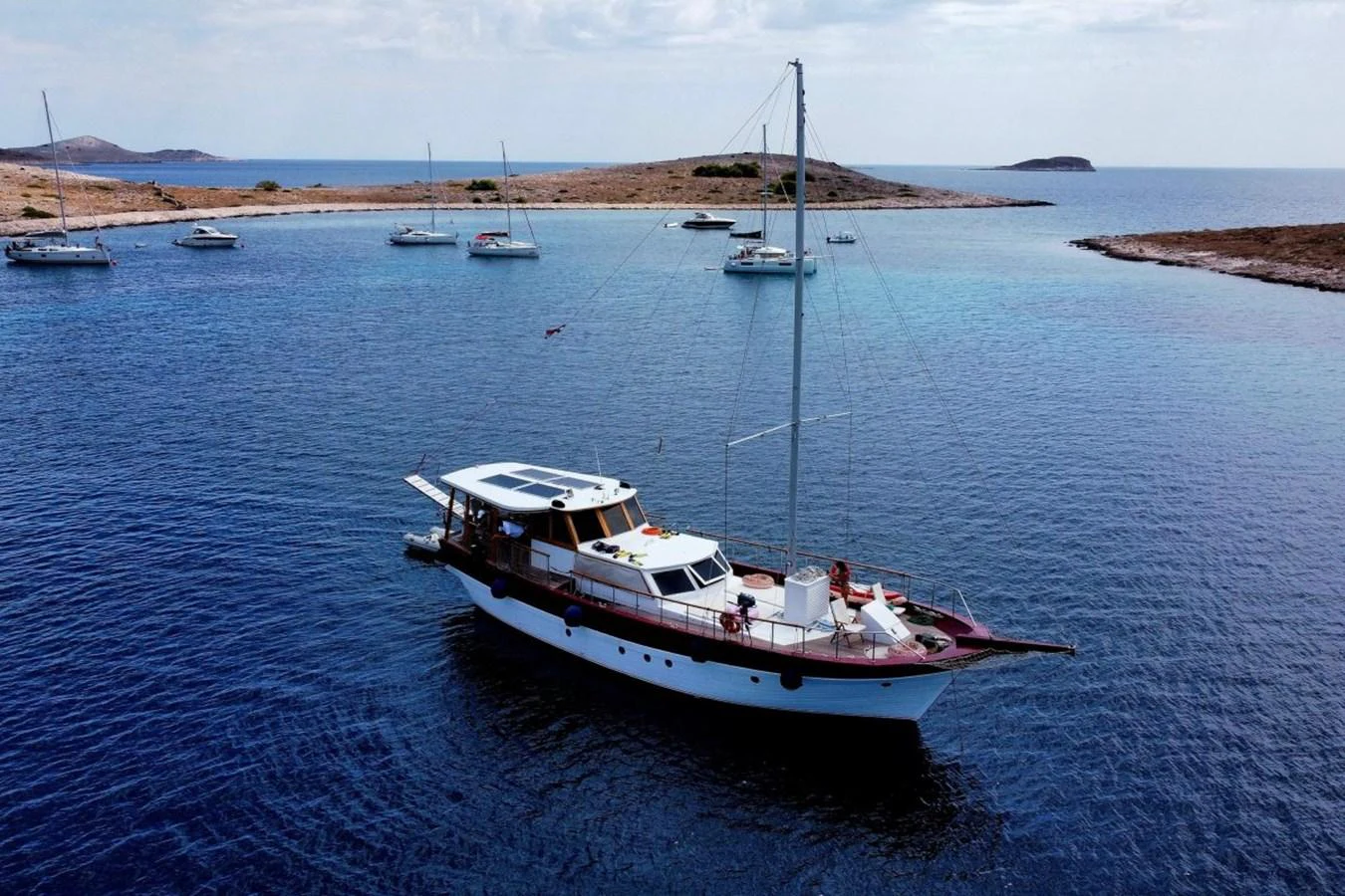 A classic yacht cruises through serene waters with a picturesque backdrop of islands and other boats. aboard 21 M MOTORSAILOR Yacht for Sale