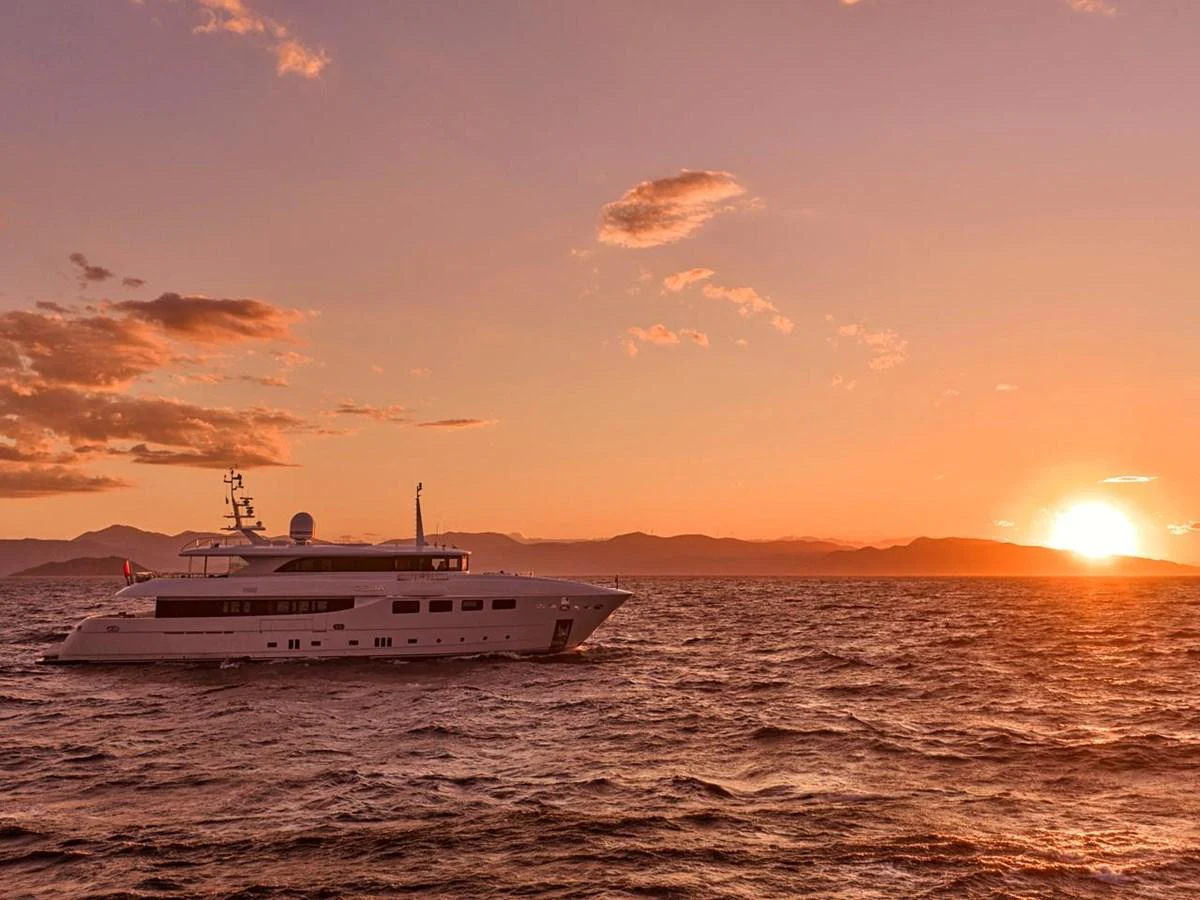 A sleek yacht cruises gracefully on the open water at sunset. aboard ULYSSES Yacht for Sale