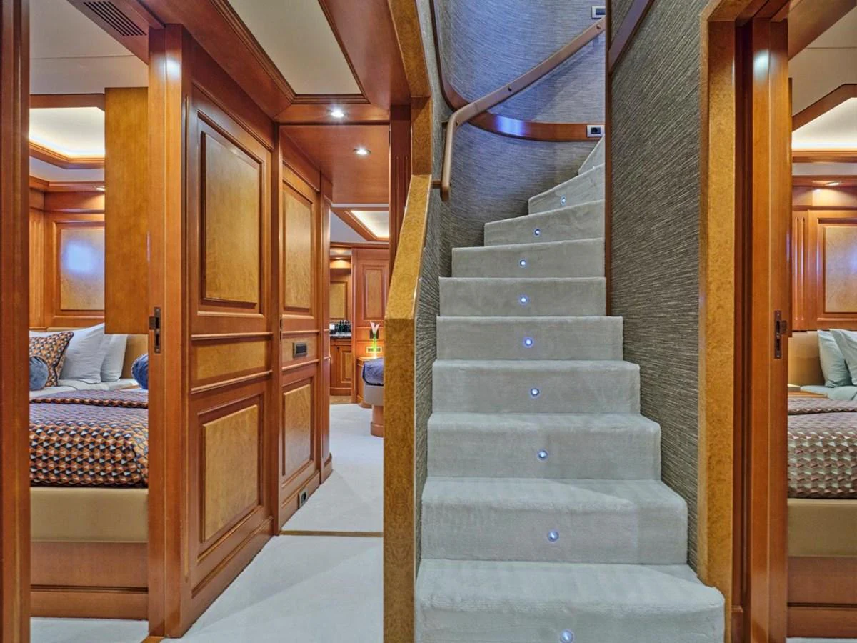 The image showcases a luxurious interior stairway with elegant wood paneling and plush carpeting. aboard ULYSSES Yacht for Sale