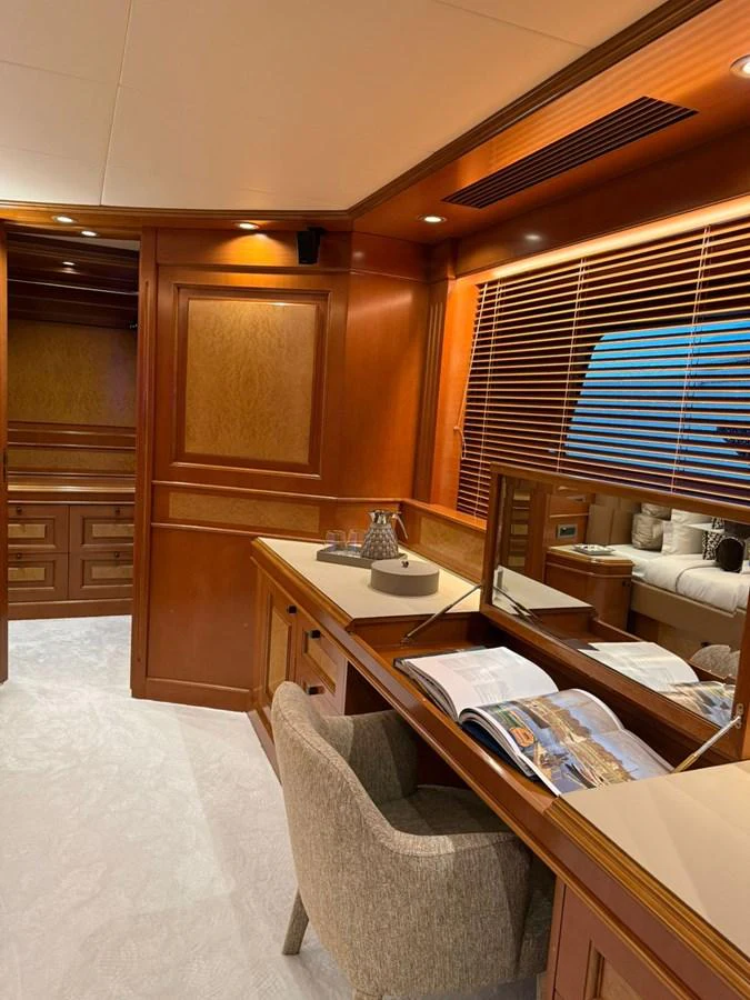 A luxurious yacht interior featuring a cozy workspace with wooden finishes and a comfortable chair. aboard ULYSSES Yacht for Sale