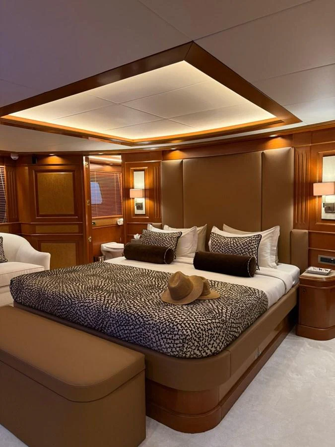 The master stateroom features a luxurious bed with elegant bedding and warm wood finishes. aboard ULYSSES Yacht for Sale