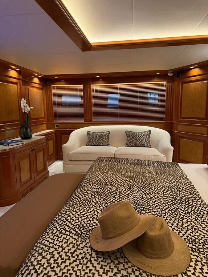 The stateroom features elegant wood paneling, a cozy sofa, and a stylish bed with patterned linens. aboard ULYSSES Yacht for Sale