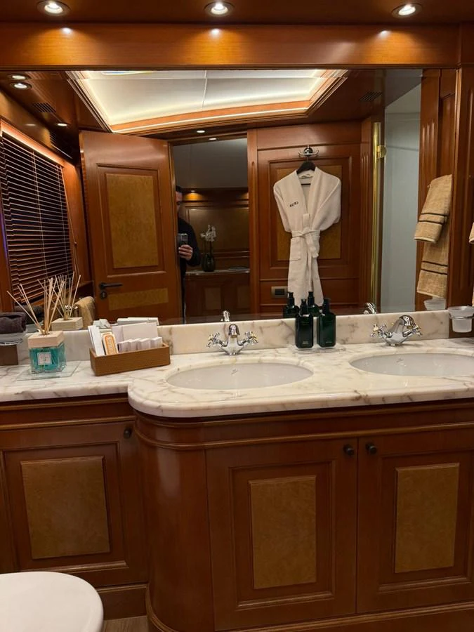 The yacht's bathroom features elegant wood paneling, a marble countertop with dual sinks, and luxurious amenities. aboard ULYSSES Yacht for Sale