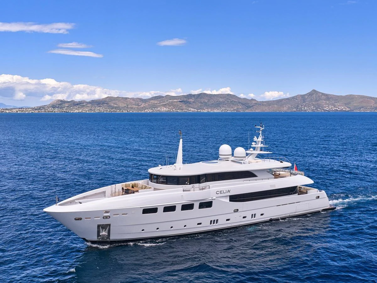 A sleek and modern yacht cruises through calm blue waters with a scenic mountainous backdrop. aboard ULYSSES Yacht for Sale