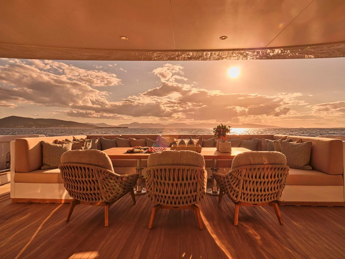 The aft deck features a luxurious seating area with a stunning view of the sunset over the water. aboard ULYSSES Yacht for Sale