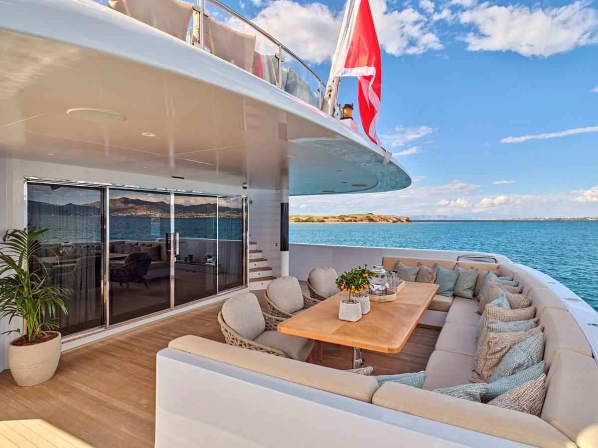 The aft deck features a spacious seating area with a dining table, perfect for enjoying meals with a view of the sea. aboard ULYSSES Yacht for Sale