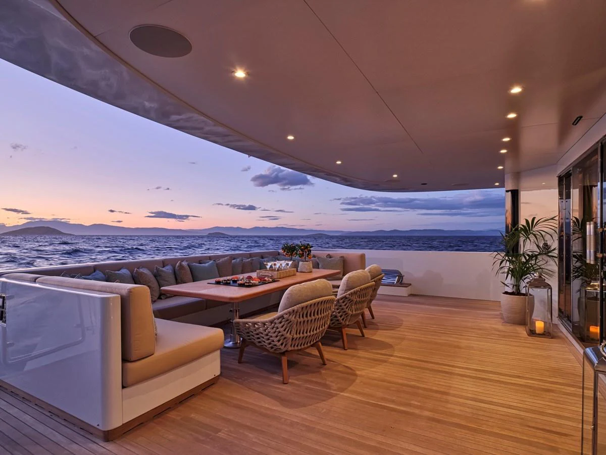 The aft deck offers a luxurious outdoor dining area with stunning ocean views at sunset. aboard ULYSSES Yacht for Sale