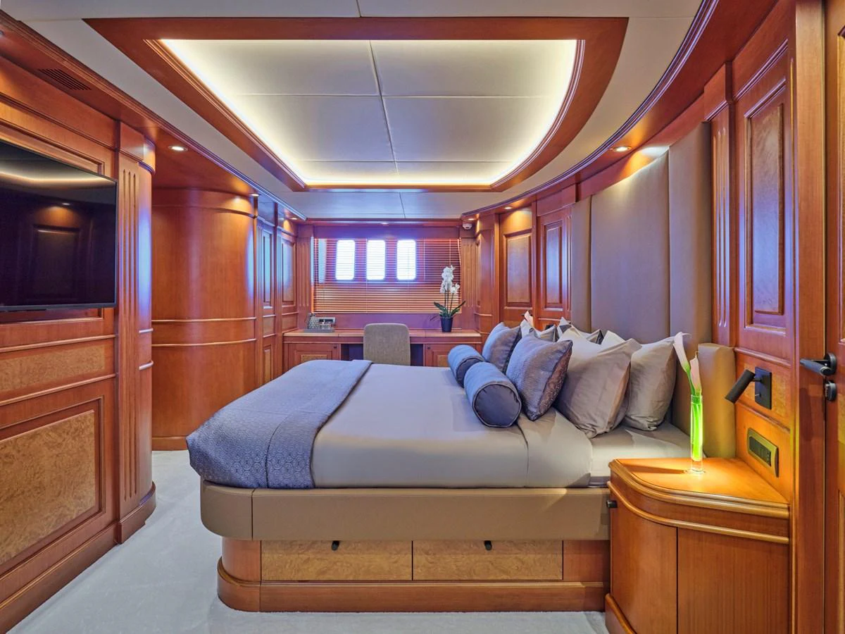 The master stateroom features elegant wood paneling and a luxurious bed with plush pillows. aboard ULYSSES Yacht for Sale
