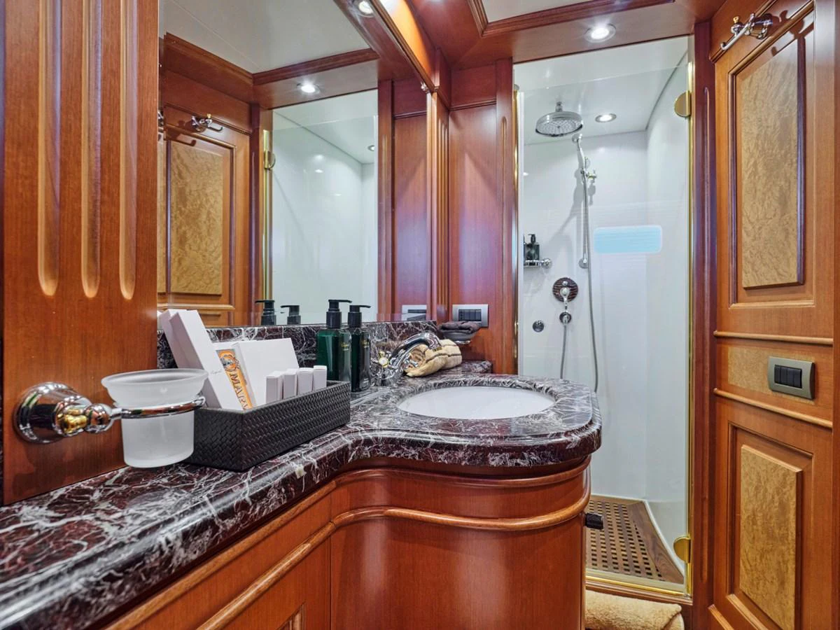 The yacht's bathroom features elegant wood paneling and a luxurious marble countertop. aboard ULYSSES Yacht for Sale