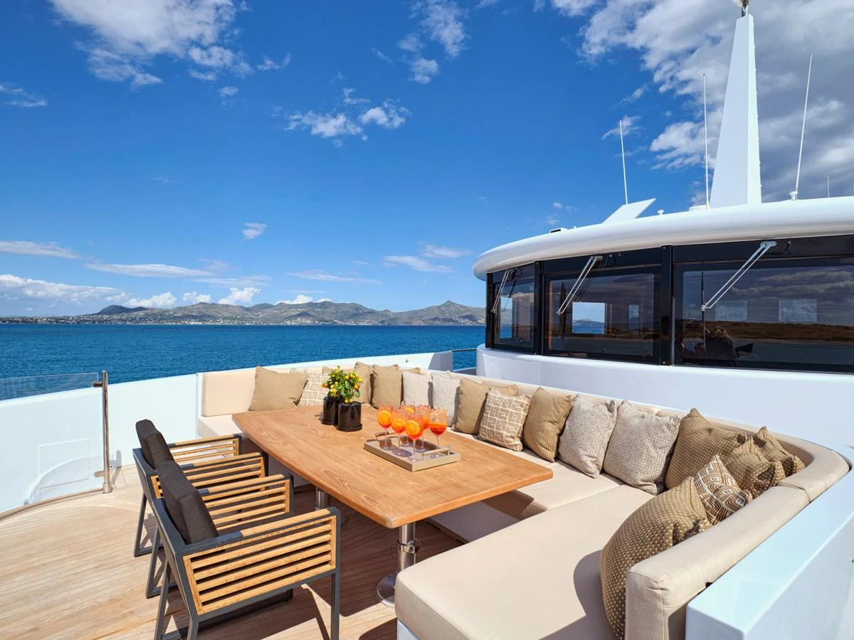 The aft deck features a comfortable seating area with a large table, perfect for outdoor dining and relaxation. aboard ULYSSES Yacht for Sale