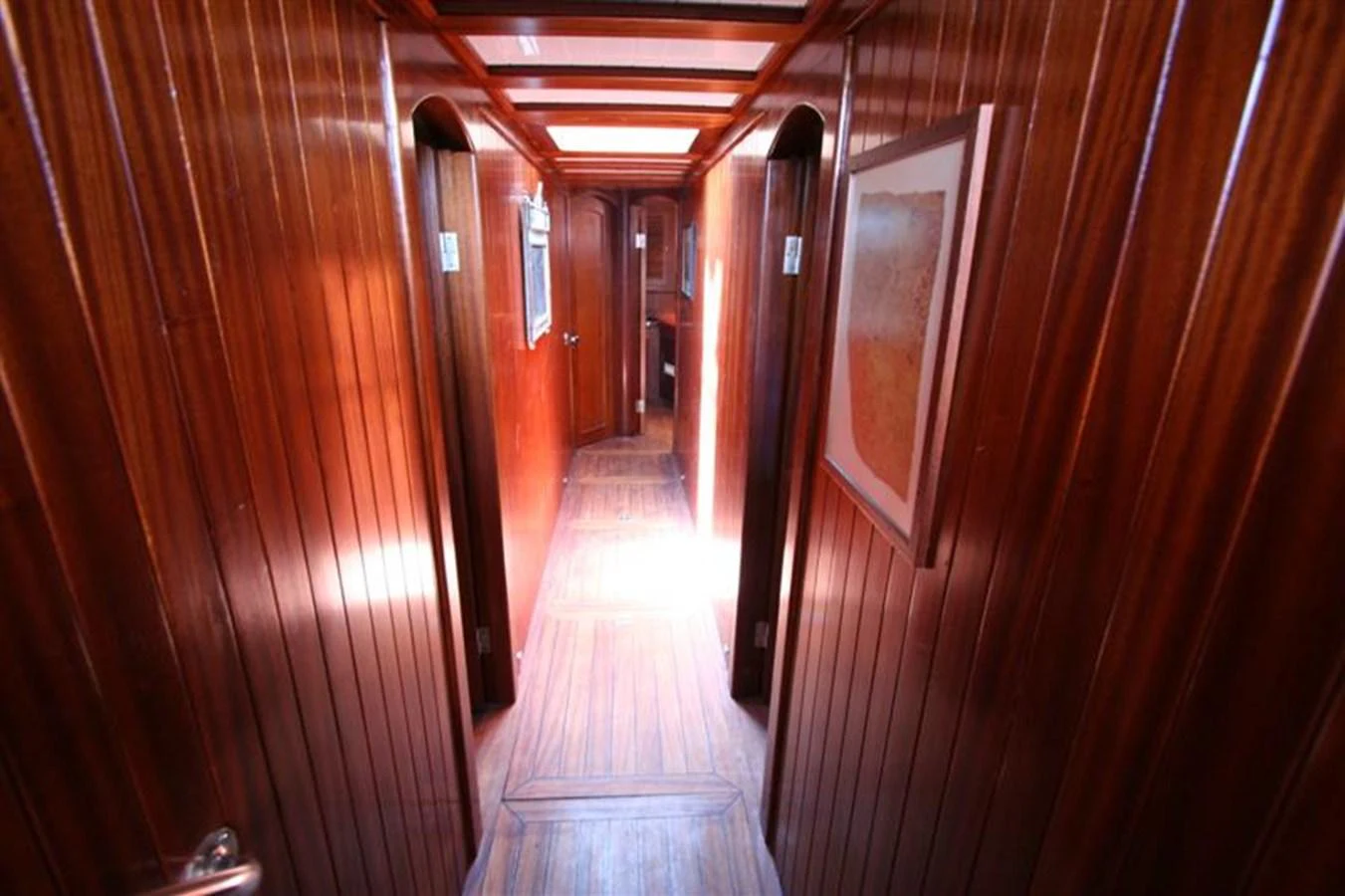 A warm, wood-paneled hallway leads to various rooms on the yacht. aboard TRIPPIN Yacht for Sale