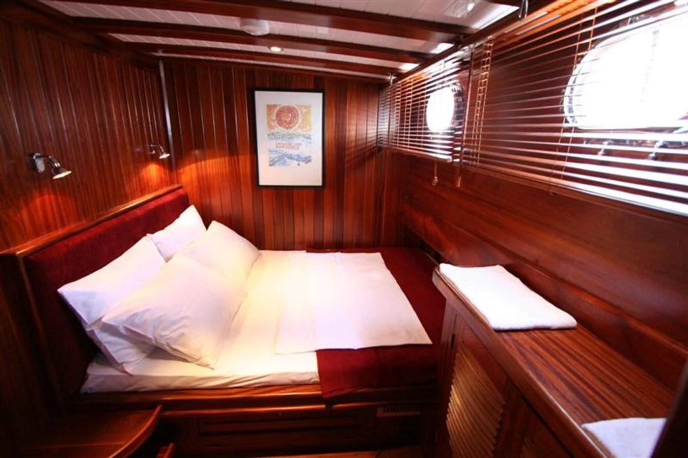 The stateroom features rich wood paneling, a comfortable bed, and ample natural light from portholes. aboard TRIPPIN Yacht for Sale