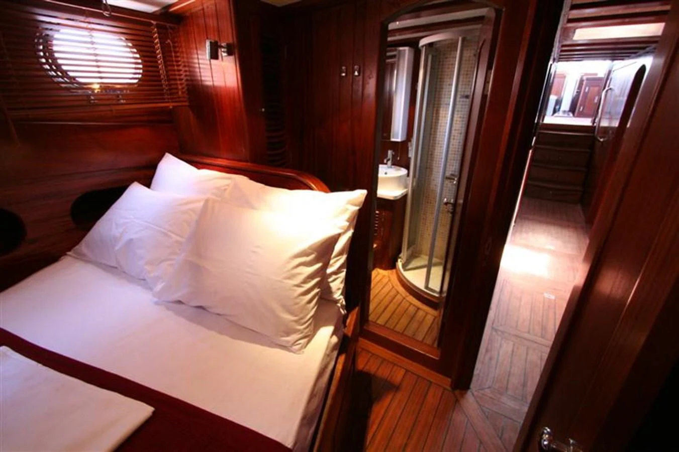 A cozy stateroom featuring a comfortable bed and an en-suite bathroom with wooden finishes. aboard TRIPPIN Yacht for Sale