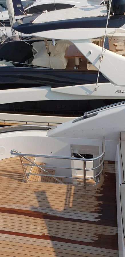 The aft deck features a staircase leading to the upper levels, with sleek railings and wooden flooring. aboard LEOPARD 105 FT Yacht for Sale