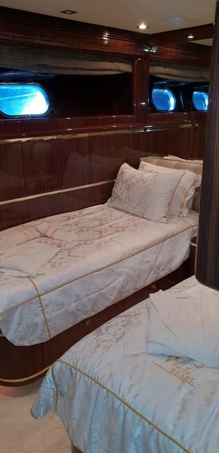The guest stateroom features twin beds with elegant bedding and rich wood paneling. aboard LEOPARD 105 FT Yacht for Sale