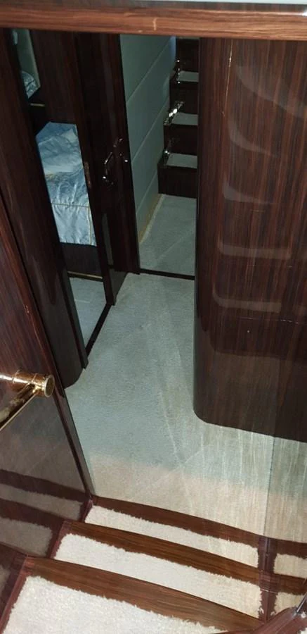 The image shows a section of the yacht's interior with dark wood finishes and a glimpse of a bed. aboard LEOPARD 105 FT Yacht for Sale