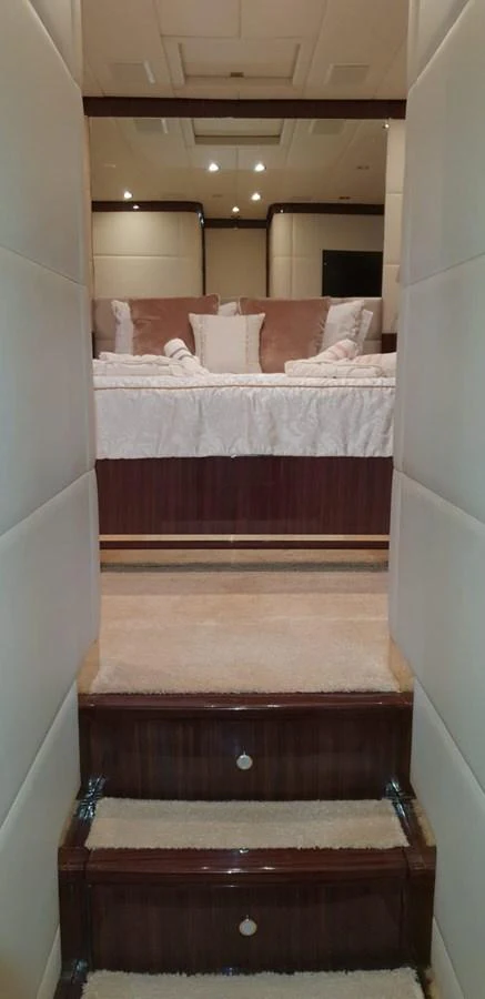 A cozy stateroom with plush bedding is accessed via a short staircase. aboard LEOPARD 105 FT Yacht for Sale