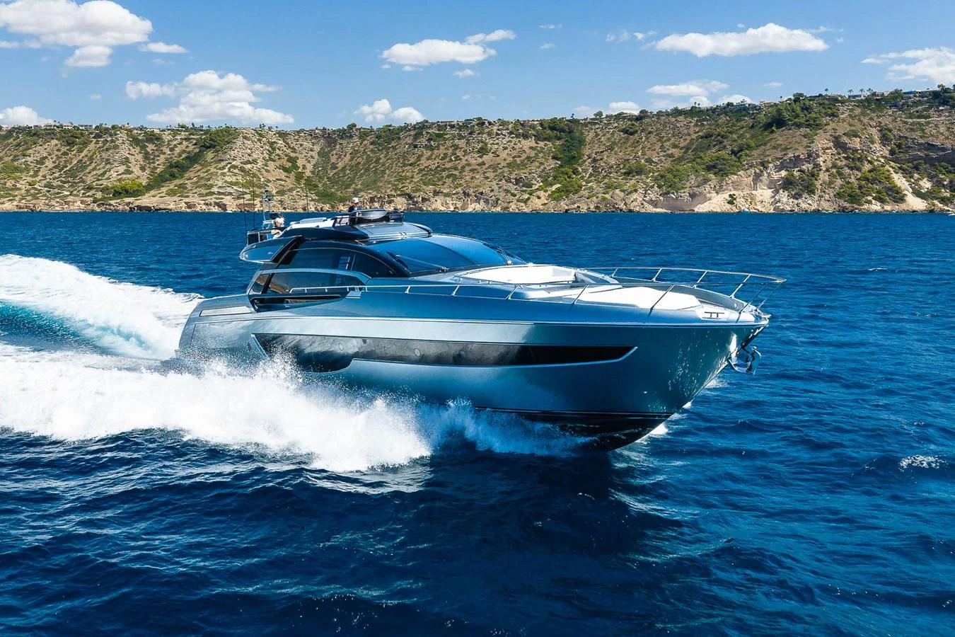 A sleek and modern yacht cruises swiftly through the vibrant blue waters, showcasing its elegant design against a scenic coastal backdrop. aboard ACQUA Yacht for Sale