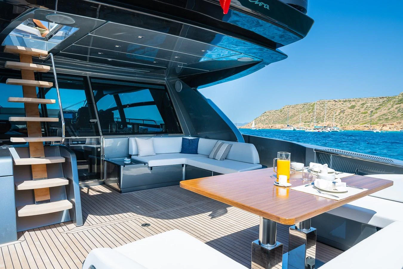 The aft deck features a stylish seating area and a dining table with a scenic ocean view. aboard ACQUA Yacht for Sale