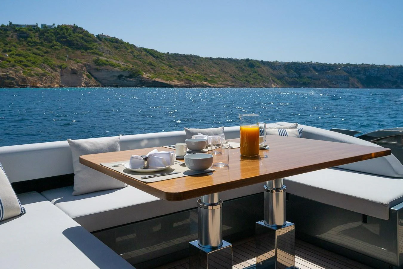 The aft deck features a stylish dining area with a stunning view of the coastline. aboard ACQUA Yacht for Sale